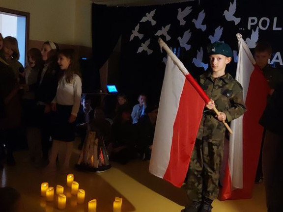 Obraz przedstawia Występ klasy 3a i 3c z okazji 104 rocznicy Odzyskania Niepodległości przez Polskę